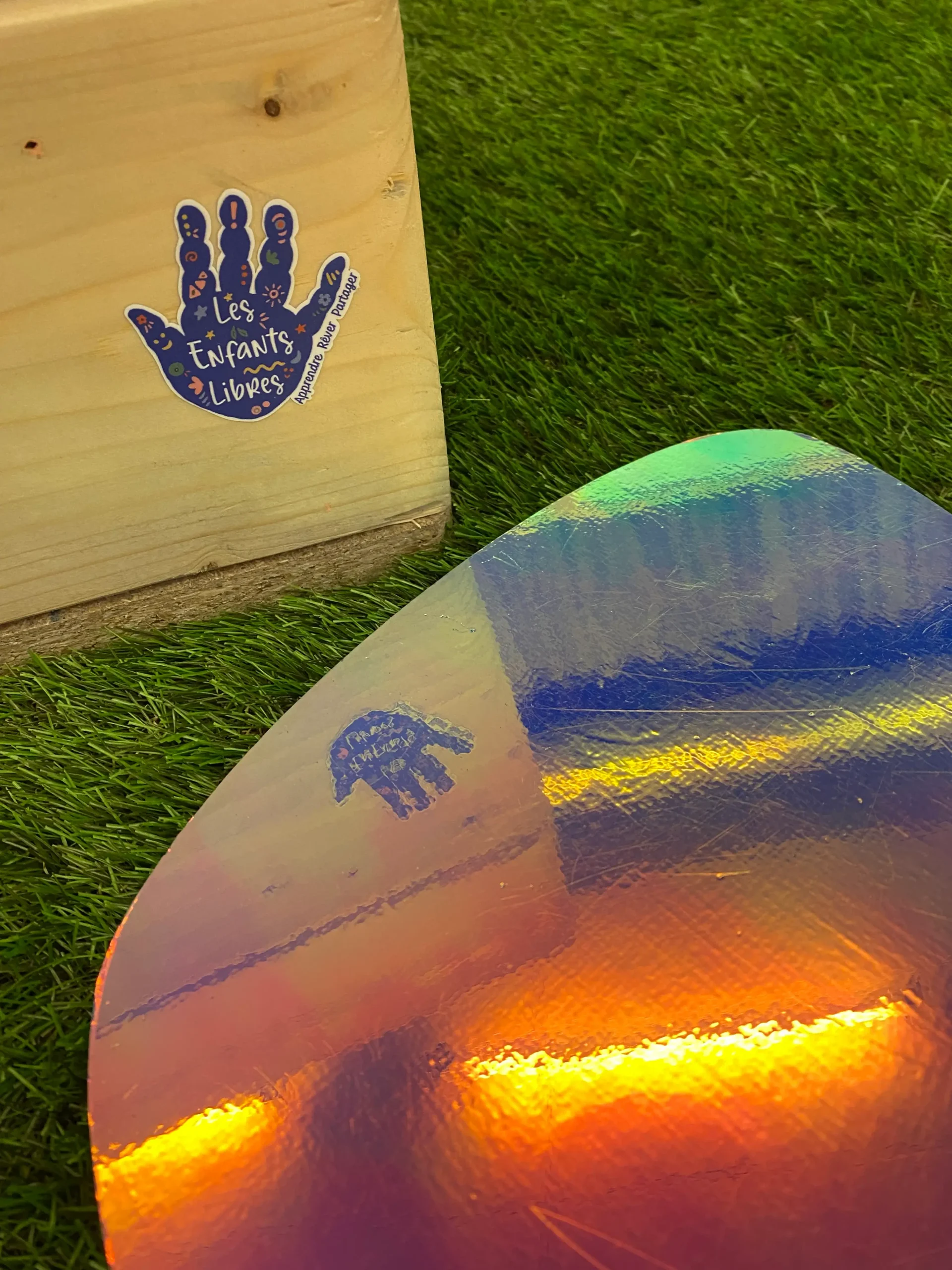 Autocollant "Les Enfants Libres" apposé sur un tunnel sensoriel, avec son reflet projeté sur un pas japonais sensoriel à effet miroir, lors de l’exposition Dans la peau d’un jardinier